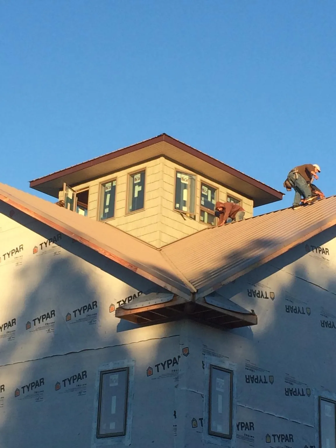 Roofers working around a rooftop cupola on a new metal roof at sunset — Roof Waterproofing in Brookline by Roofing Brothers